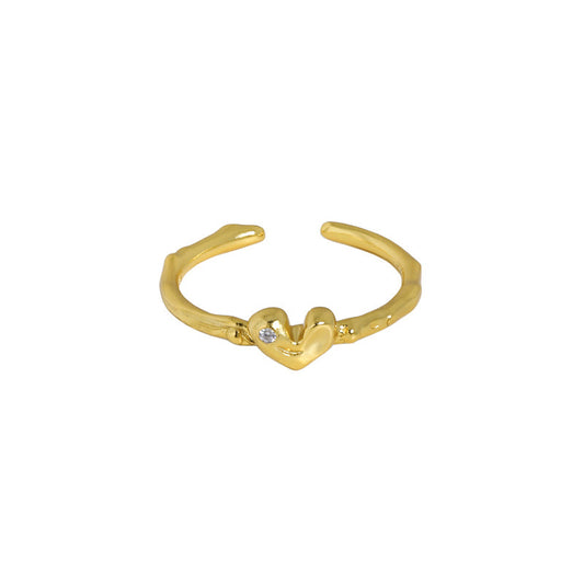 A sterling silver gold-plated ring with a thin band, adorned with a dainty heart motif featuring a tiny cubic zirconia. Perfect for stacking or as a standalone piece, this ring exudes minimalist charm, symbolizing timeless connections with an added touch of sparkle. The overall design creates an organic, unconfined texture, reminiscent of nature's beauty.